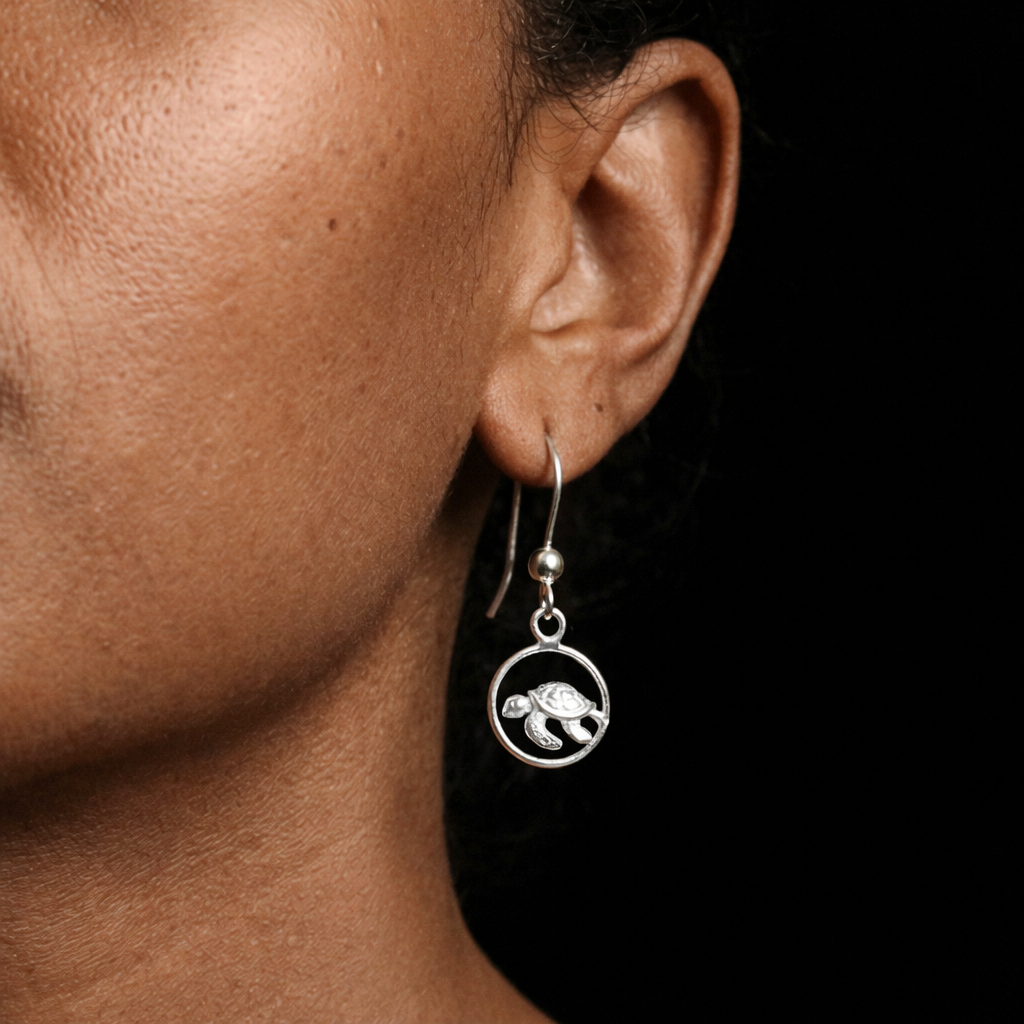 Silver earring with a circular design worn by a person against a black background