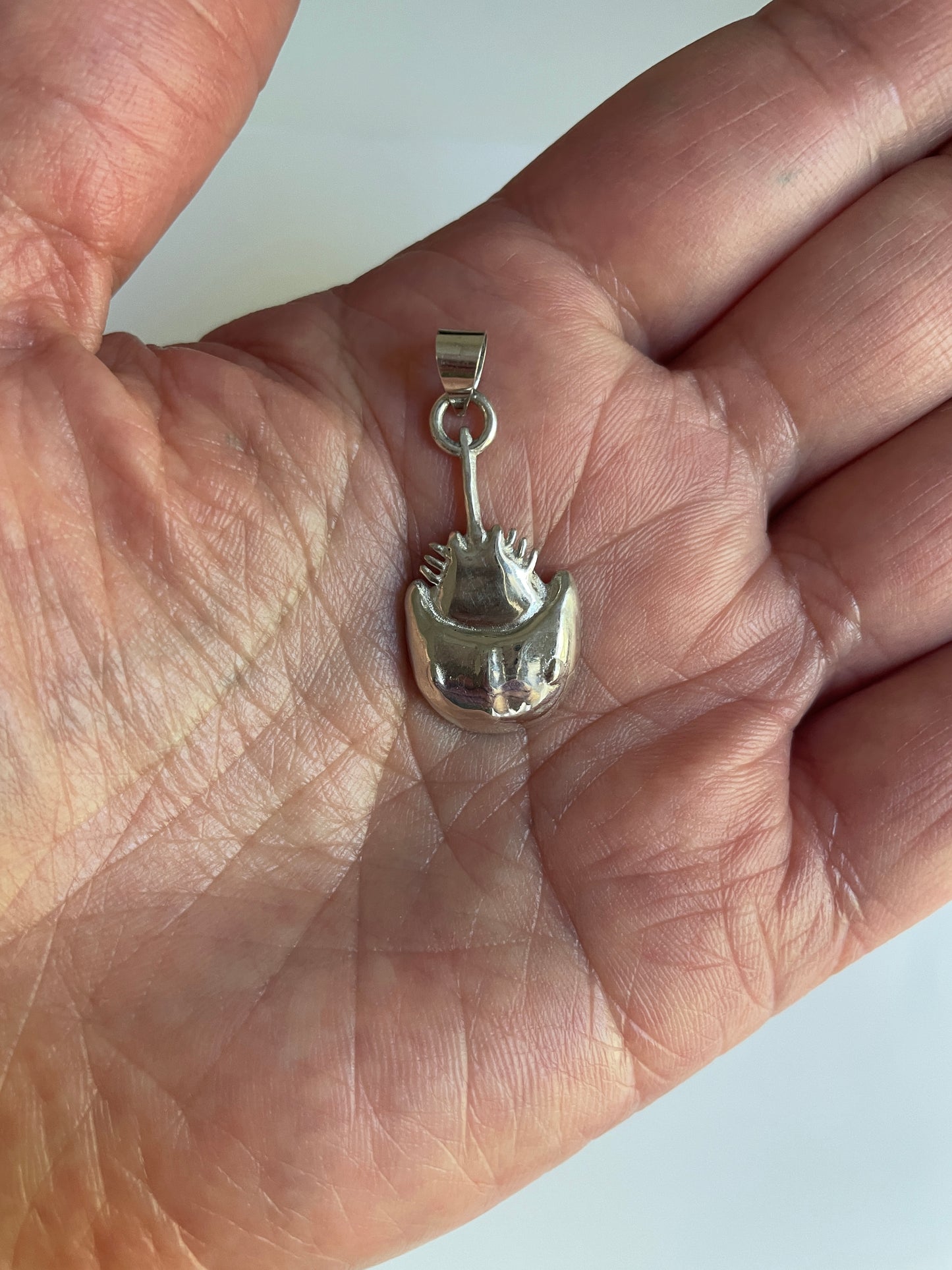 Horseshoe Crab Charm on Hand in white background