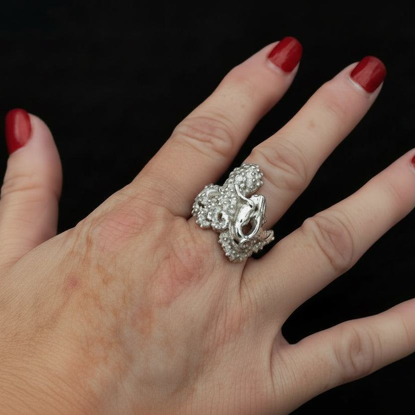 Hand wearing a silver ring with red nail polish on a black background