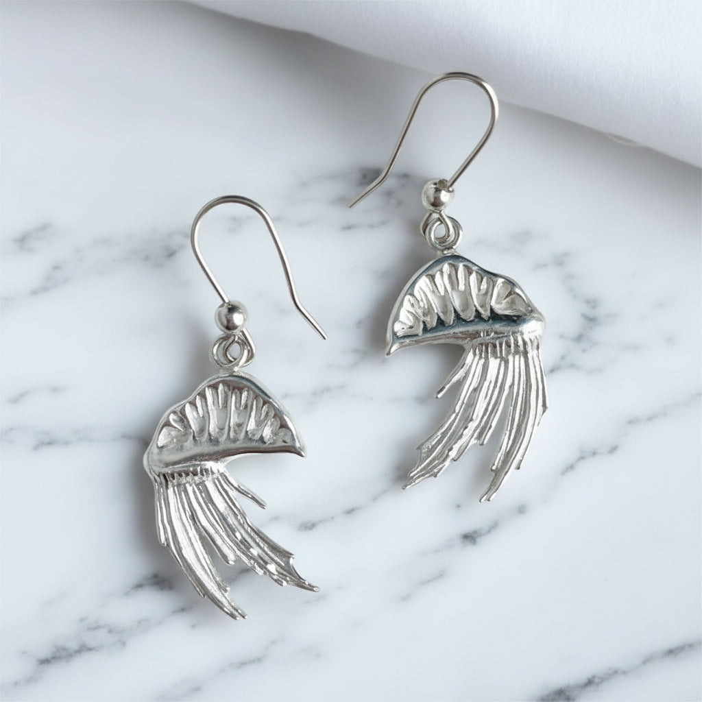 Silver Man o war earrings on white marble