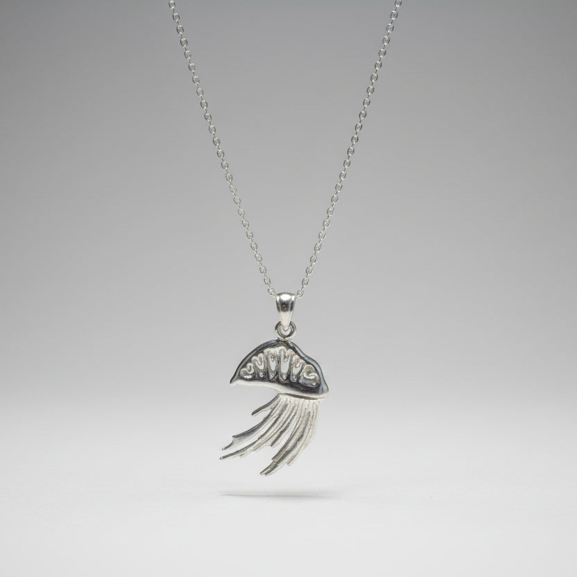 Silver Portuguese man o war necklace with a decorative pendant on a white surface