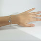 Silver bracelet with a crab charm on a wrist against a neutral background