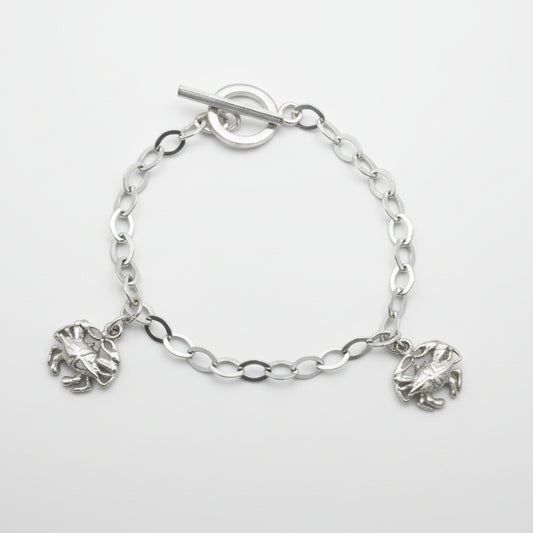 Silver chain bracelet with crab charms on a light gray background