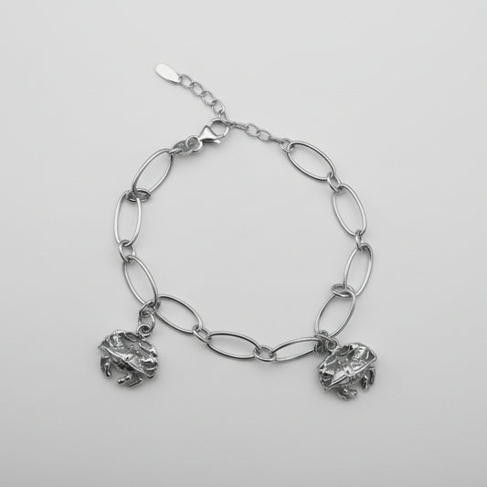 Silver chain bracelet with crab charms on a gray background