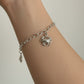 Silver chain bracelet with crab charm on a wrist against a neutral background
