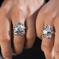 Close-up of two hands wearing silver rings with star designs on a neutral background