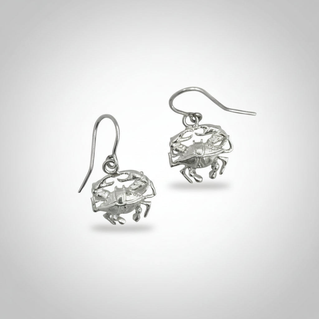 Pair of silver crab-shaped earrings on a light gray background
