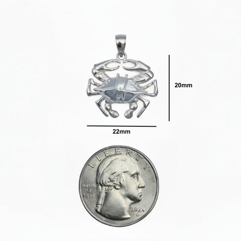 Silver crab pendant with measurements and a comparison to a quarter coin on a white background