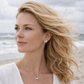 Woman with blonde hair and a white top standing on a beach.