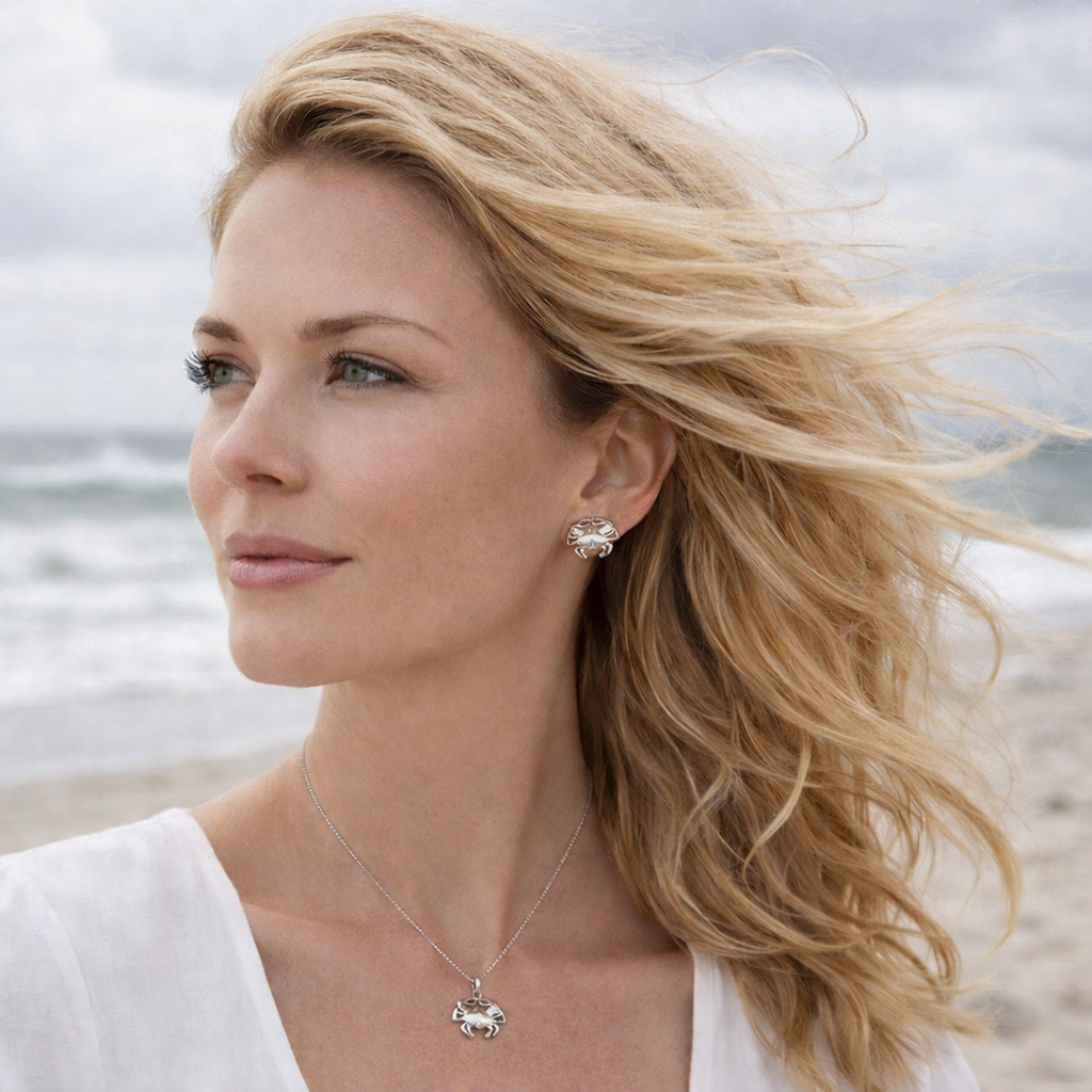 Woman with blonde hair and a white top standing on a beach.
