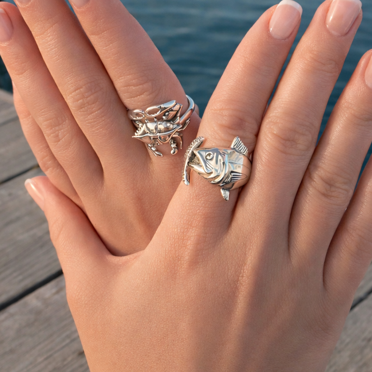 Hand wearing multiple silver rings with a blurred water background