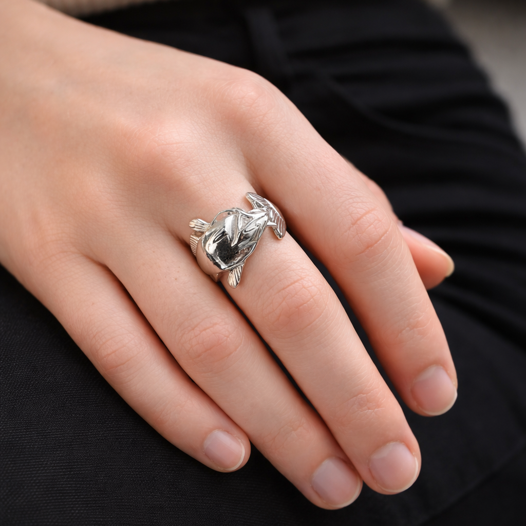 Close-up of a hand wearing a silver ring with a catfish profile.