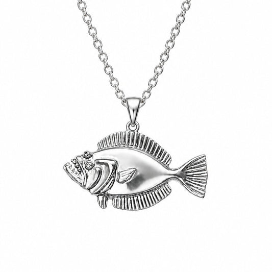 A silver fish pendant with detailed scales and a textured fin, held in a person's hand against a plain light background.