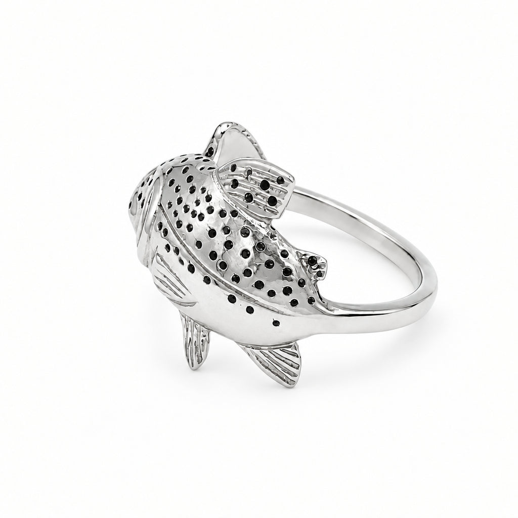 A sterling silver fish ring with detailed black spots and textured scales, shown on a whtie background.