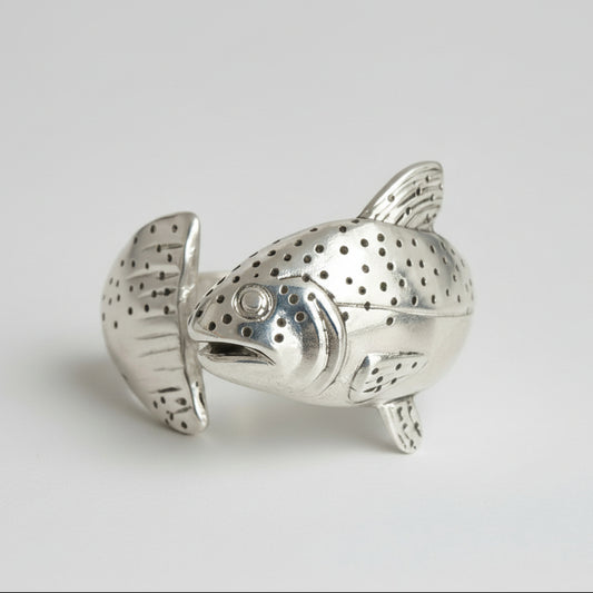 Silver fish-shaped tea infuser on a light gray background