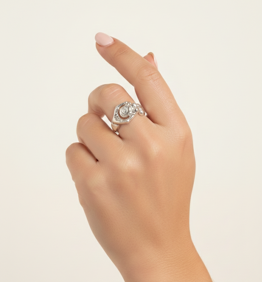 Hand wearing a silver ring on a light beige background