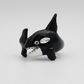 Black and silver orca whale figurine on a white background