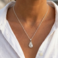 Woman wearing a silver necklace with a pendant outdoors