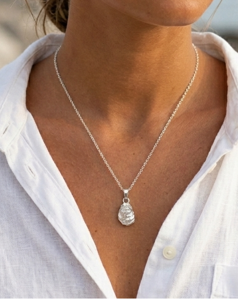 Woman wearing a silver necklace with a pendant outdoors