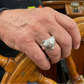 man wearing silver fish ring placing his hand on boat wheel