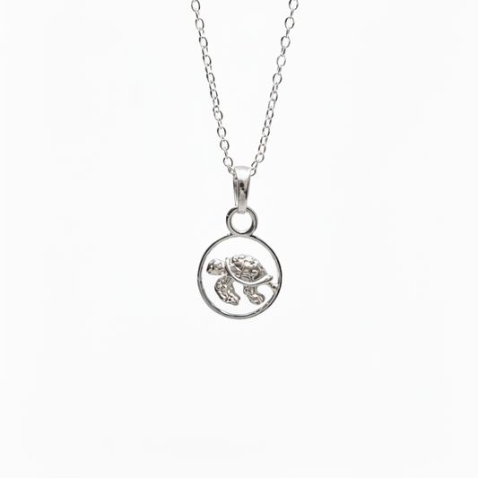 A silver necklace featuring a circular pendant with a small sea turtle design, shown against a plain white background.