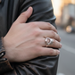 Hand wearing a silver ring on a blurred street background