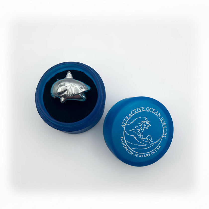 Blue jewelry box with a shark ring on a light gray background