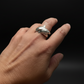 Hand wearing two silver shark tooth rings on a dark background