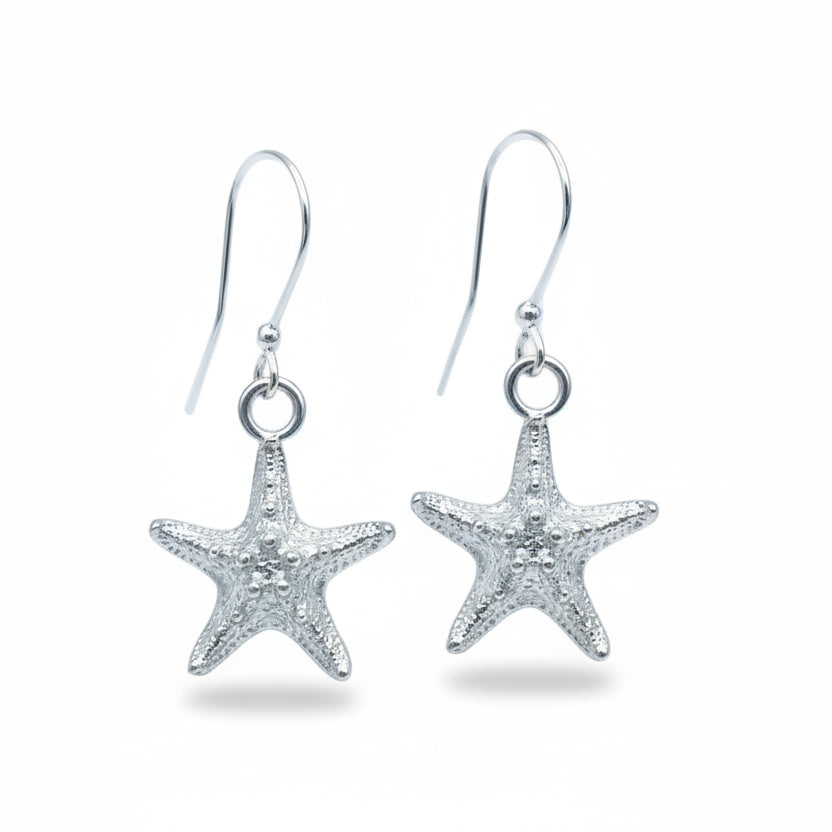 A pair of silver starfish dangle earrings with textured starfish charms and silver fishhook wires, displayed on a light blue background.