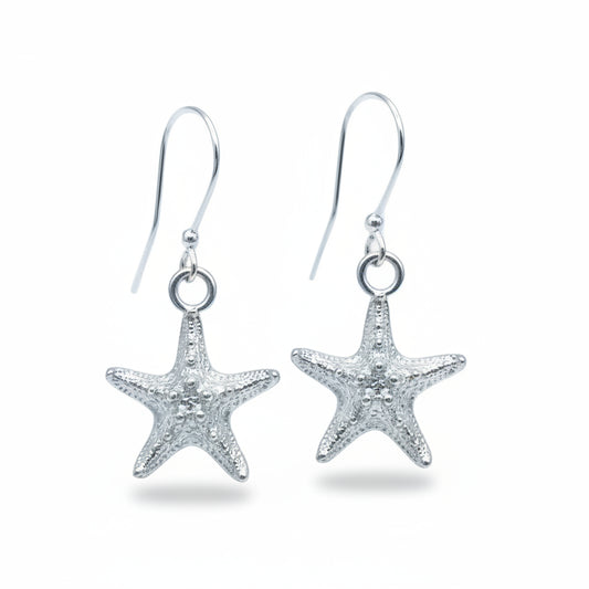 A pair of silver starfish dangle earrings with textured starfish charms and silver fishhook wires, displayed on a light blue background.