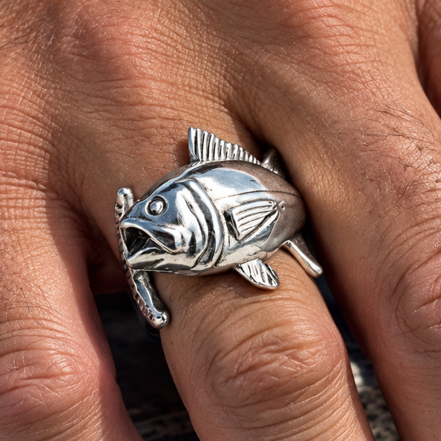 A silver fish ring worn on a finger, featuring a detailed tuna fish design , shown in a close-up lifestyle shot.