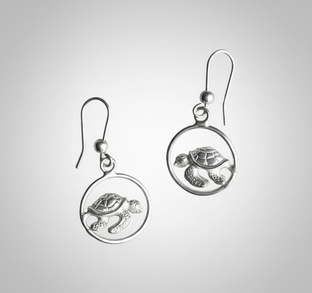 Silver turtle earrings on a light gray background
