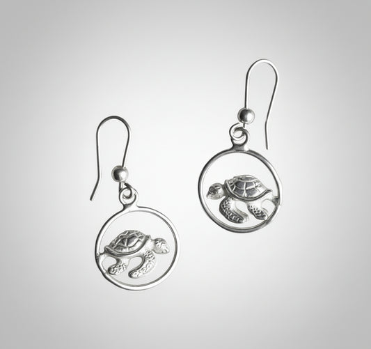 Silver turtle earrings on a light gray background