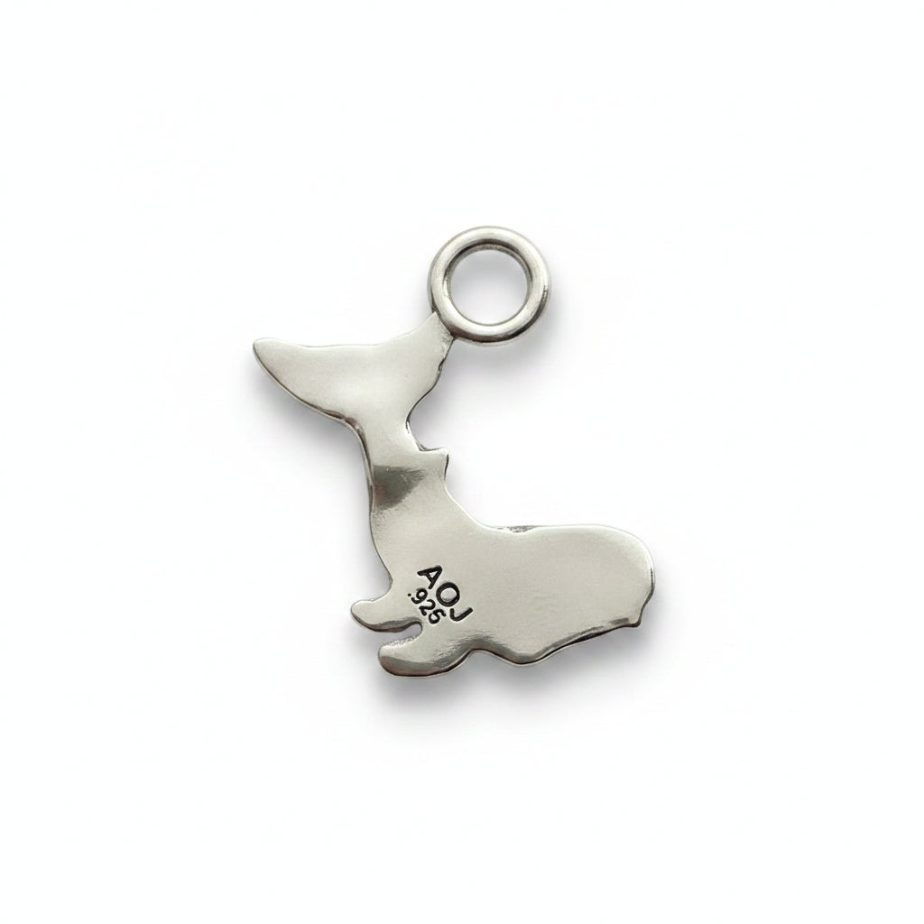 Silver charm shaped like a whale on a white background